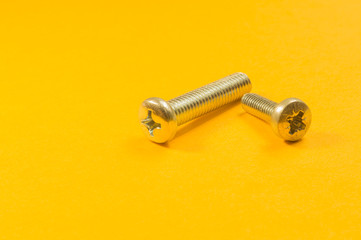 Screws on a yellow background. pile of fasteners