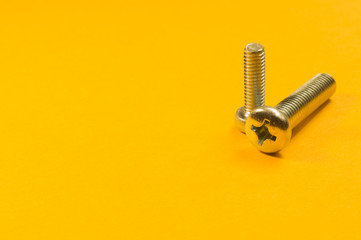 Screws on a yellow background. pile of fasteners