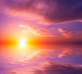 Fototapeta premium Beautiful pink sea sunset with bright sun and clouds.