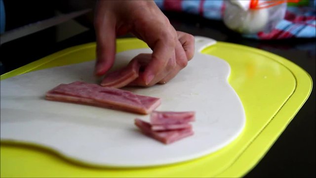 Steady video shot of a person’s hand slicing ham