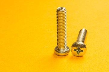 Screws on a yellow background. pile of fasteners
