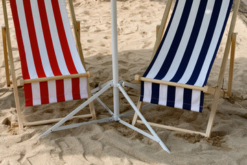 two sun loungers in the shade on sand