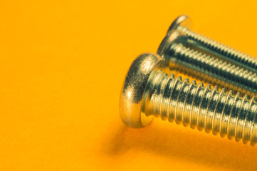 Screws on a yellow background. pile of fasteners