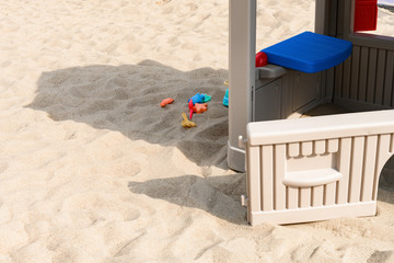 toy house and plastic shovel etc on sand in a sunny day