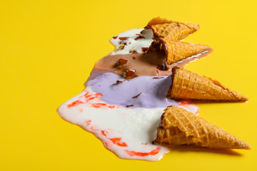 side view multiple flavor ice cream cones melted on yellow background