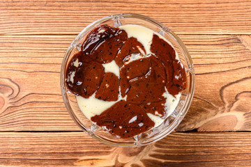 top view cup of melted chocolate ice cream on a wood table