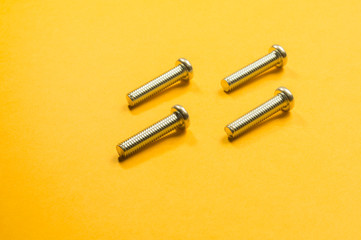 Steel screw on a yellow background