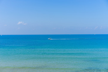 Fototapeta na wymiar Calm water with a boat in the distance at the beach in Tel Aviv, Israel