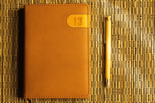 Diary and pen on a wooden bamboo background. notebook and pen top view. number 13