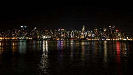 Fototapeta na wymiar Manhattan skyline at night with reflections off water New York City NYC
