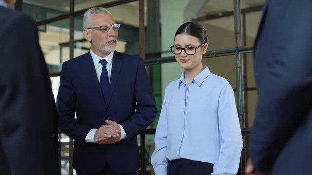 Mature boss introducing new female colleague in office, coworkers shaking hands