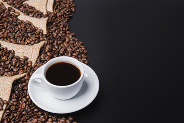 cup of coffee with beans on black background with copy space