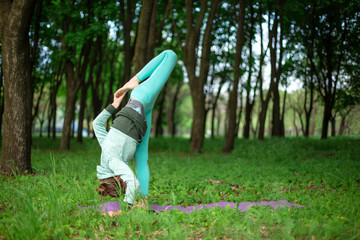 Thin brunette girl plays sports and performs beautiful and sophisticated yoga poses in a summer...