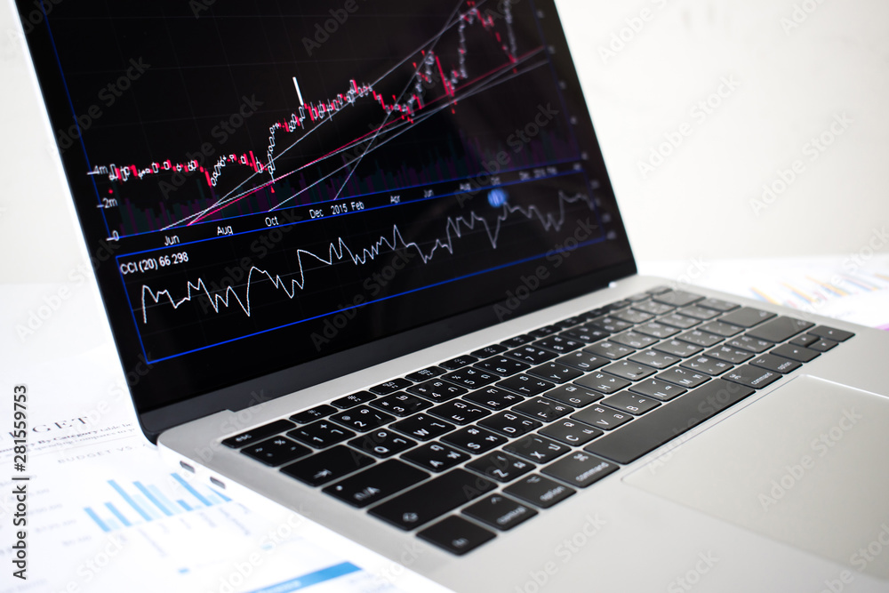 Poster laptop computer image showing financial graph on screen with documents on the desk.