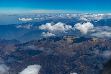 Fototapeta premium Mountain range above the clouds from an airplane