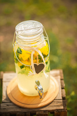 Homemade lemonade sale concept. Lemons, mint, cocktail cans in boxes for lemonade close-up. Homemade lemonade in dispenser and copy space.