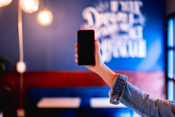 Girl holding a phone with a black screen with an office in the background