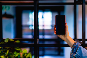 Girl holding a phone with a black screen with an office in the background