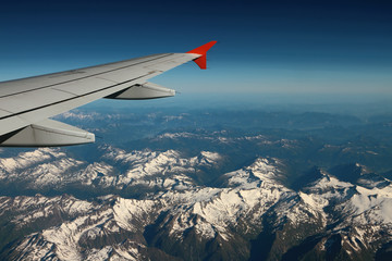Fototapeta na wymiar Under plane wing snow-covered mountain tops. Austria-Italy