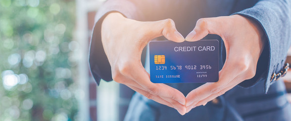 Woman hand are holding a credit card and making a heart-shaped hand.
