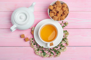 Cup of tea with sugar cubes and flower branches on wooden table close up