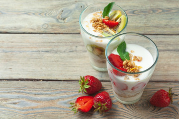 glass of healthy strawberry yogurt with fresh berries on wooden table top view
