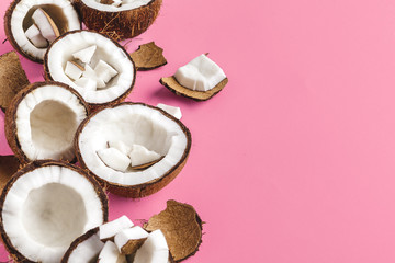 Broken coconut pieces on bright pink background, top view, copy space
