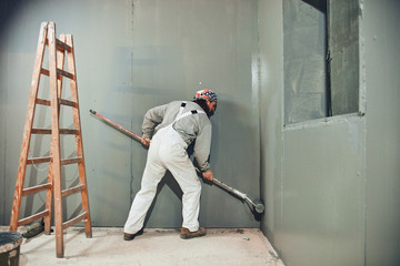 Painter painting walls with a extender roller indoors.