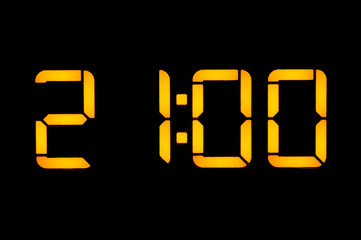 Electronic digital clock with orange numbers on a black background shows the time Twenty-one zero...