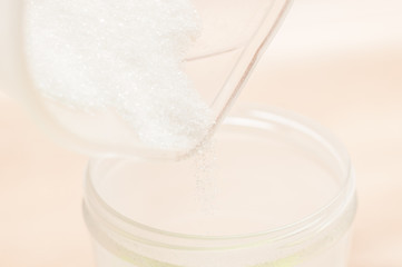 Pouring white sugar into a smaller container for ease of use