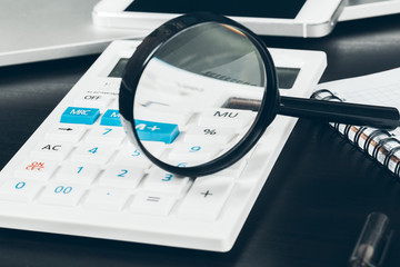 Stationery items on the table. Calculator and magnifying glass close up