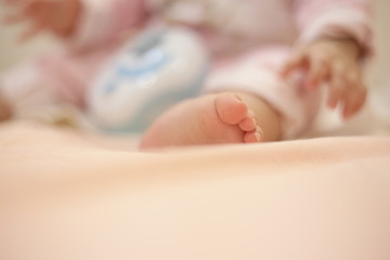 small baby sitting. close up image of baby leg and feet. healthy and happy infant sitting on her own. toddler sat on bed. happy new family concepts.