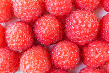 Raspberry closeup on a light wooden background. Ripe bright berries. The concept of a fresh crop of berries, delicious vitamin food, organic products. Place for text.
