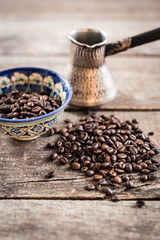 Coffee beans  in a coffeepot or turk on a wooden background