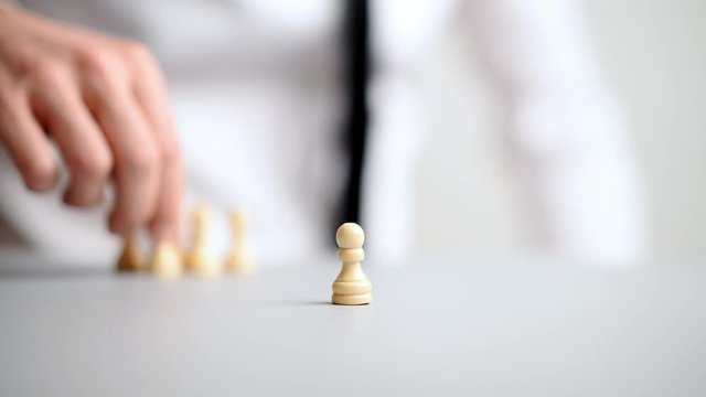 Businessman placing pawn chess figures on white table