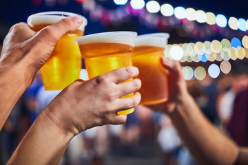 Friends drinking beer at night with de-focused lights in the background. Shallow focus.