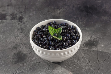 Fototapeta na wymiar Fresh organic blueberries in a bowl on dark background close up.