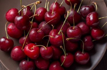 Cherries on a plate, on a wooden background. Summer picnic, harvest, treats. Food for vegetarians and vegans. Proper nutrition, healthy lifestyle, diet, diabetes