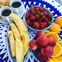 blue tablecloth with fruit on it. melon, peach and strawberry