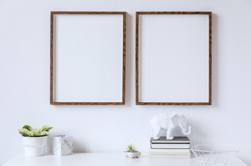 Stylish white home decor of interior with two brown wooden mock up photo frames on the white shelf...