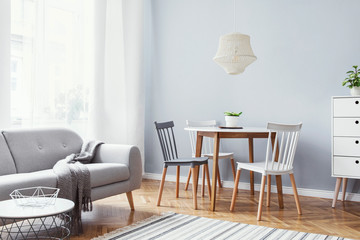 Scandinavian stylish decor of home interior with design furniture, grey sofa, family table and...