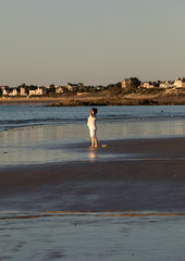 Obraz premium A woman practicing yoga on the beach of Saint Malo in the glow of the setting sun. Brittany, France
