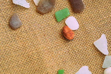 Shells, sea glasses and stones on a jute background close-up brown color toned. Vacation concept