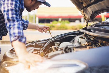 Hand traveler of car mechanic check engine oil for maintenance , Auto mechanic checking oil. Car repair service.