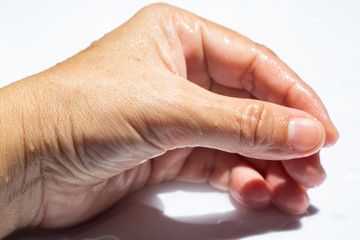 Woman's wet side hand with water drops on white acrylic background, Close up & Macro shot, Selective focus, Asian Body skin part,  Relaxing Bath, Healthcare concept