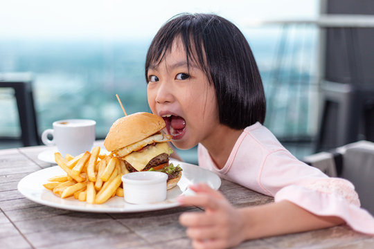 Asian Little Chinese Girl eating hamburger