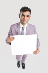 Young Indian business executive showing blank sign board over white background