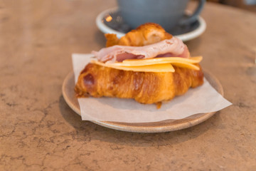 Continental breakfast with croissant and coffee. Freshly baked croissant filled with cheese, ham and bacon