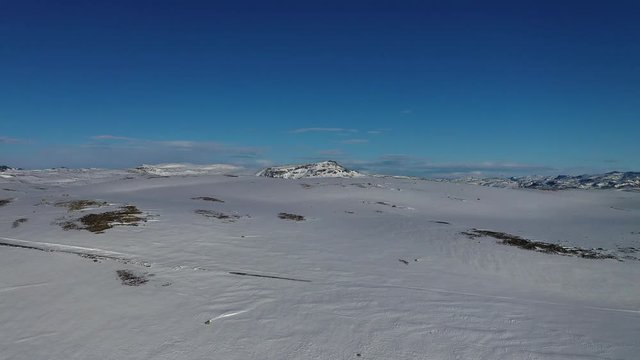 Landscape drone footage of a remote mountain in Norway covered in winter snow