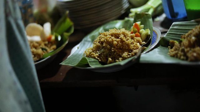Shot of a street vendor preparing their indonesian food. The meal is fried rice (Nasi Goreng) served on a banana tree leaf.